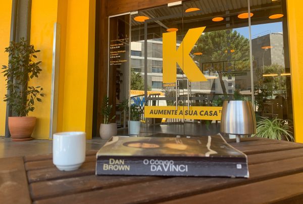 A book and a coffee cup on top of a wooden table in front of KUBOO's reception door