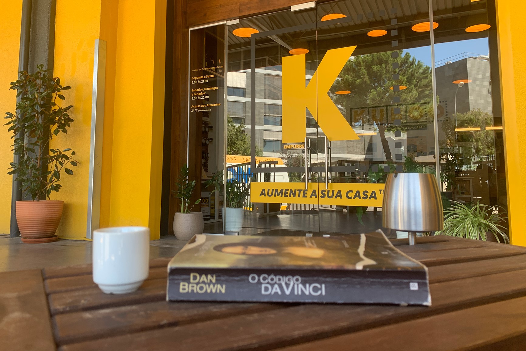 A book and a coffee cup on top of a wooden table in front of KUBOO's reception door