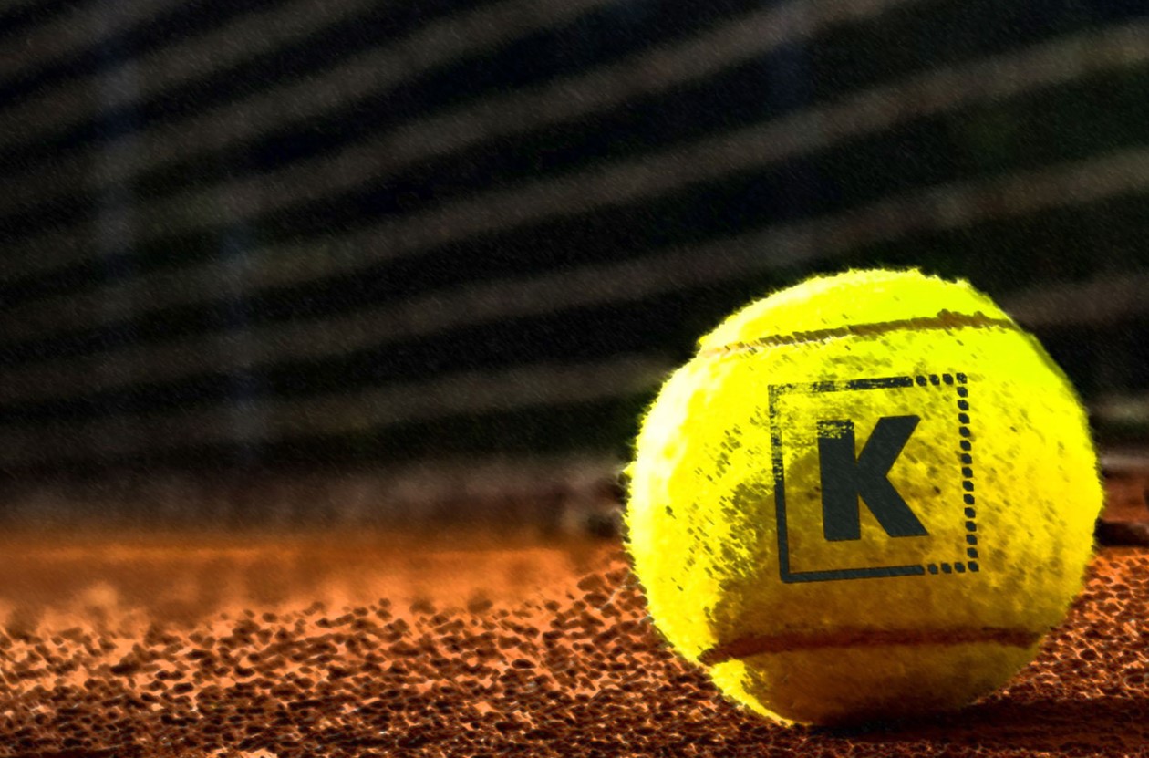 Tennis ball with KUBOO branding on a clay court