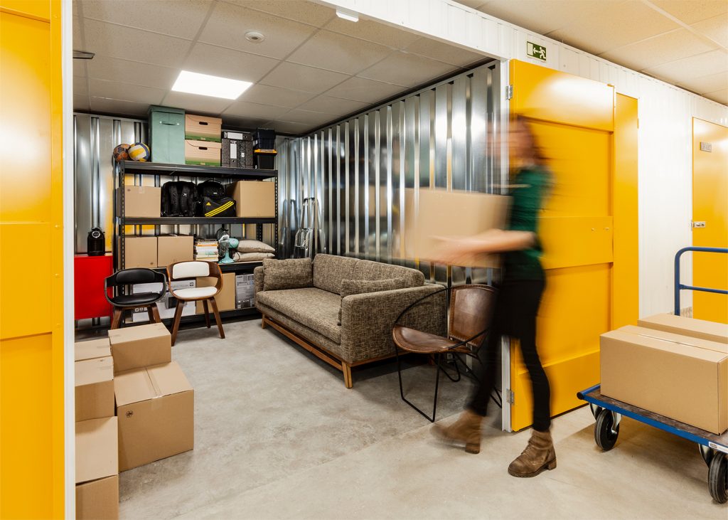 person carrying a boxes into a kuboo unit with items inside